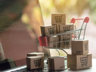 Shopping online concept - Parcel or Paper cartons with a shopping cart logo in a trolley on a laptop keyboard. Shopping service on The online web. offers home delivery.